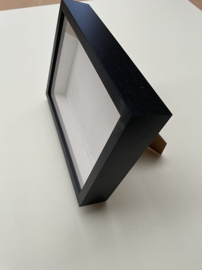 Empty black photo frame on table.