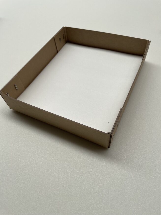 Empty cardboard pizza box on white surface.