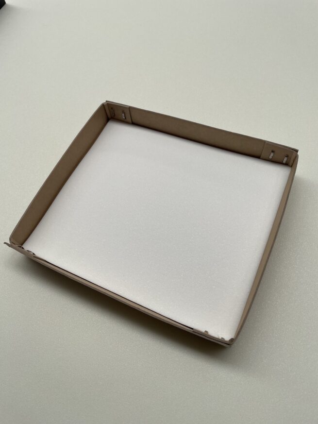 Cardboard box with foam padding on white surface